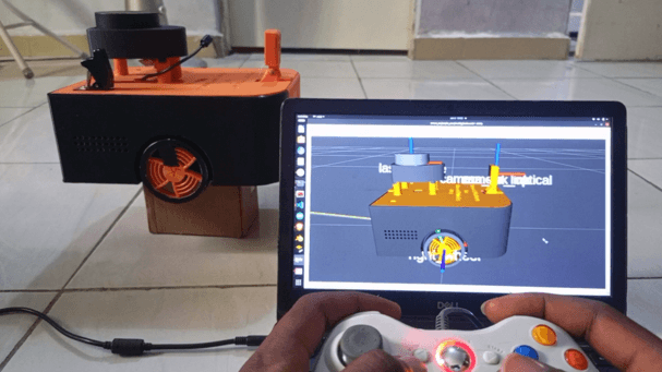 ReVolt physical robot beside its laptop simulation, with a handheld controller in the foreground